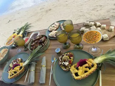 Brunch d'anniversaire dressé sur la plage à l'Île Maurice : toasts, fruits frais et jus